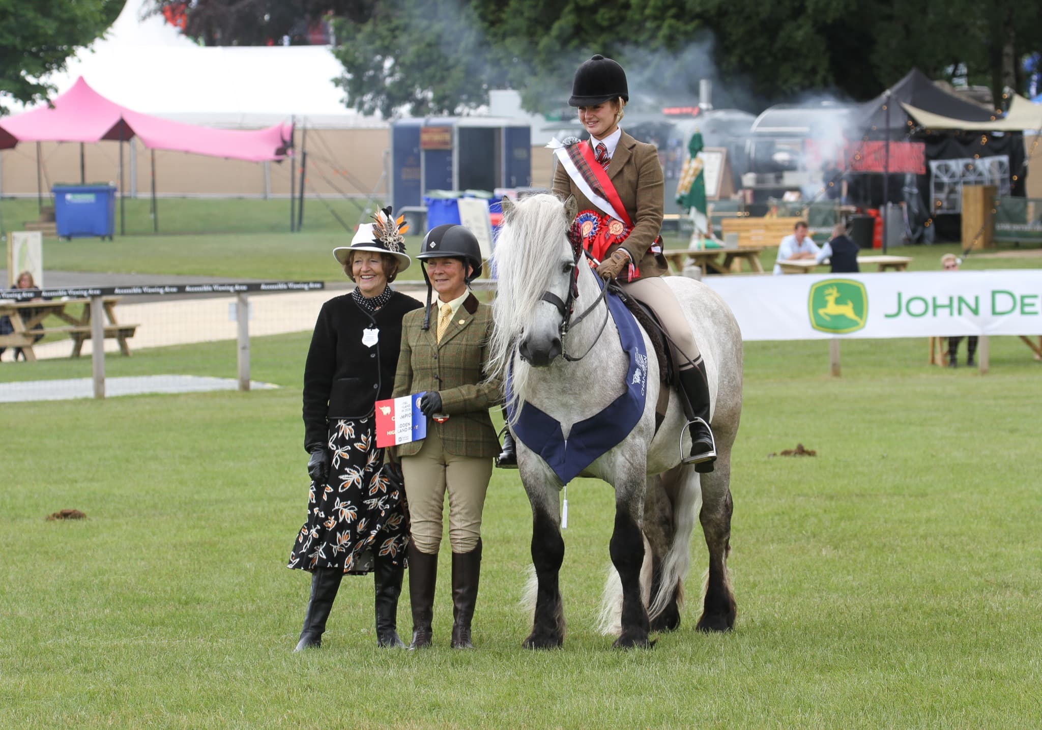 Judges presenting a championship to a ridden grey Highland pony at a show